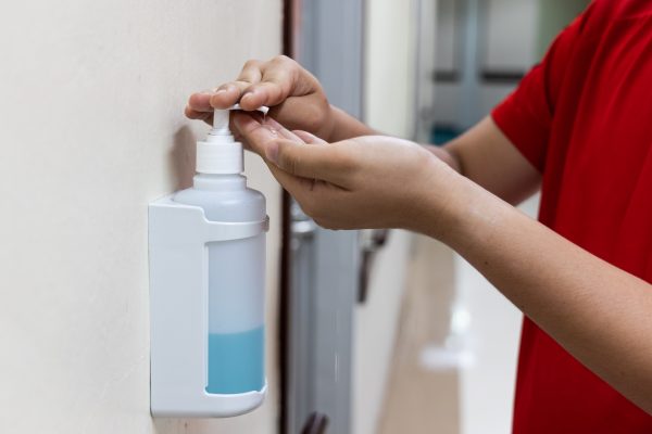 Person dispensing disinfectant sanitizer liquid onto hand in hospital for hygienic living